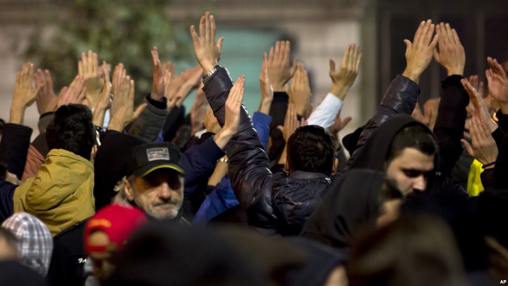 People raise their hands and shout slogans in Bucharest Romania during another day of protests calling for better governance and an end to corruption Nov. 7 2015