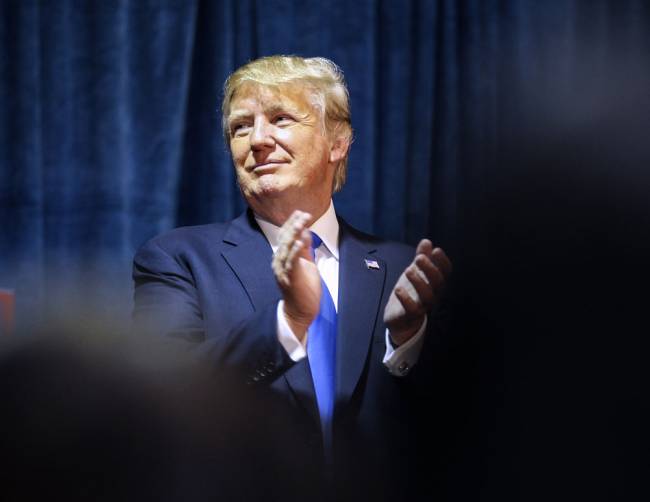 Republican presidential candidate Donald Trump claps as he looks on at his sons Eric and Donald Jr. who spoke briefly at Politics and Eggs in Manchester N.H. Wednesday Nov. 11 2015