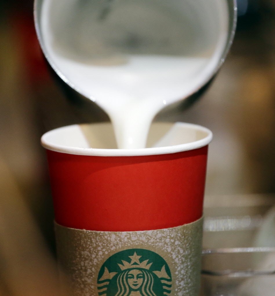 A barista pours steamed milk into a red paper cup while making an espresso drink at a Starbucks coffee shop in the Pike Place Market Tuesday in Seattle. It's as red as Santa's suit a poinsettia blossom or a loud Christmas sweater. Yet Starbucks minima