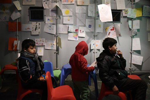 Children watch a movie at a refugee camp near the northern Greek village of Idomeni near to southern Macedonia Monday Nov. 9 2015. Migrants are facing long waits to cross Greece's border with Macedonia after a four-day ferry strike ended and ease