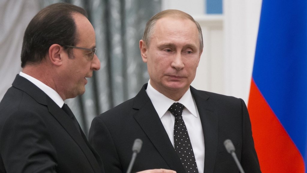 Russian President Vladimir Putin listens to French President Francois Hollande as they leave their news conference in Moscow on Thursday