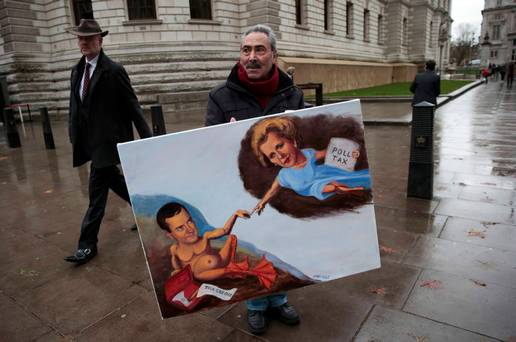 Artist Kaya Mar holds a painting depicting Chancellor George Osborne and former Prime Minister Margaret Thatcher outside of Britain's Treasury building in central London