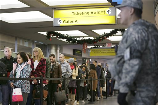 Security personnel watch as passengers wait to pass through airline security at La Guardia Airport in New York Wednesday Nov. 25 2015. An expanded version of America's annual Thanksgiving travel saga was under way Wednesday with gas prices low and