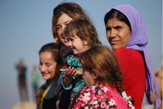 Yazidi refugees watch as others celebrate news of the liberation of their homeland of Sinjar Iraq from the Islamic State on Nov. 13. The report found the Yazidis were intentionally targeted for the purpose of destroying in whole or in part their religio