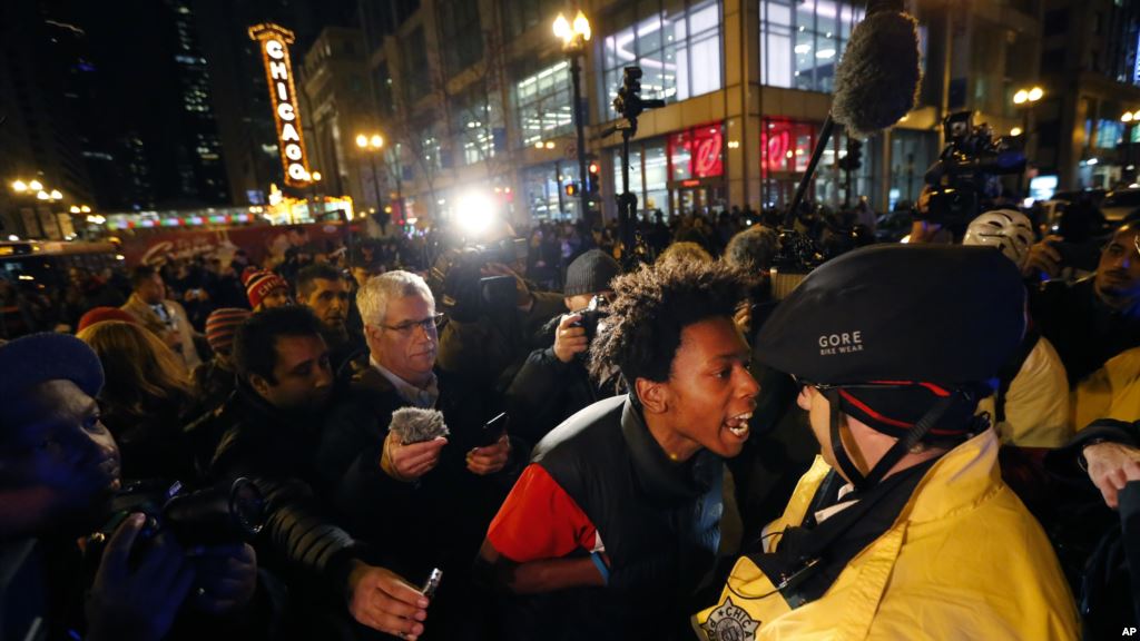 Lamon Reccord second from right yells at a Chicago police officer'Shoot me 16 times as he and others march through Chicago's Loop Wednesday Nov. 25 2015