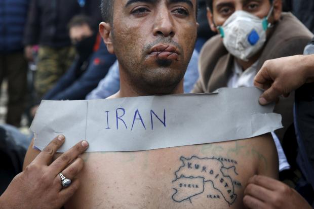 A stranded Iranian migrant has his lips sewn as he sits on rail tracks at the border between Greece and Macedonia