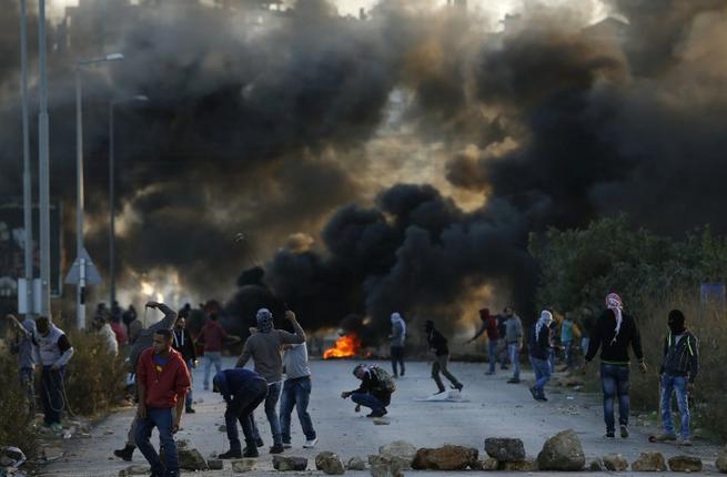 Palestinian protesters throw stones towards Israeli security forces during clashes at the entrance of the Palestinian town of Al Bireh on the outskirts of Ramallah in the Israeli-occupied West Bank