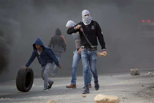 Palestinian protesters prepare to throw stones towards Israeli troops during clashes outside Ofer military prison near the West Bank city of Ramallah Tuesday Nov. 3 2015