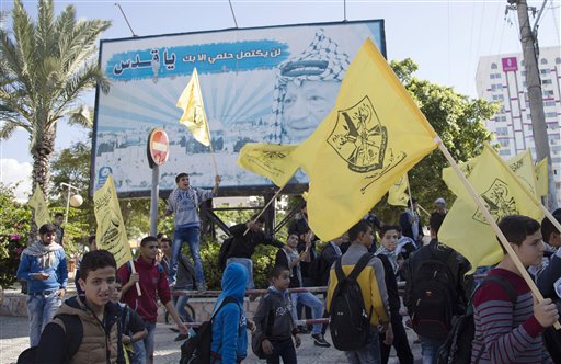 Palestinian students wave yellow Fatah flags in front of a billboard of late Palestinian President Yasser Arafat during a celebration marking the 11th anniversary of his death in Gaza City Wednesday Nov. 11 2015. Arabic reads' my dream not complete