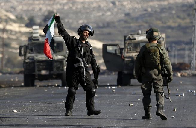 An Israeli soldier holds a Palestinian flag seized from protesters during clashes following a demonstration by Palestinians against Israeli occupation in the Palestinian town of al Bireh on the outskirts of Ramallah in the West Bank