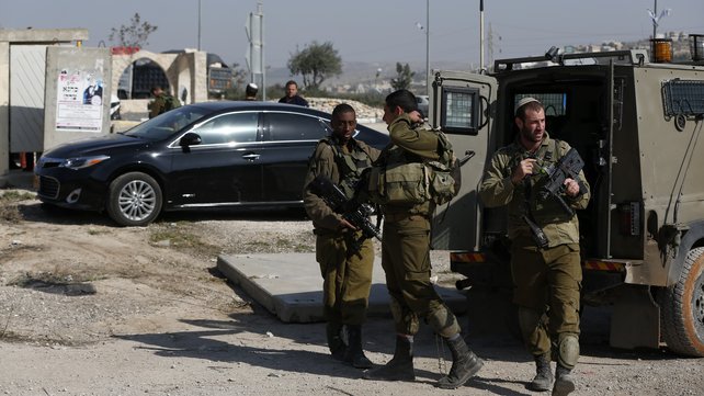 Israeli soldiers stand next to a car where a Palestinian woman tried to stab an Israeli and was shot dead