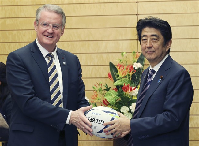 World Rugby Chairman Bernard Lapasset gives a rugby ball as a gift to Japanese Prime Minister Shinzo Abe during a meeting at Abe's official residence in Tokyo Monday Nov. 9 2015