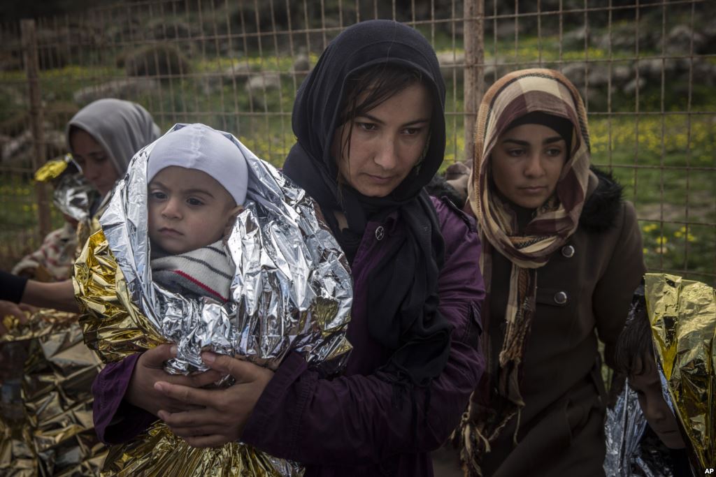 FILE- Women and children stand on a road after their arrival on a dinghy with other refugees and migrants from the Turkish coast to the Greek island of Lesbos on Wednesday Nov. 25 2015