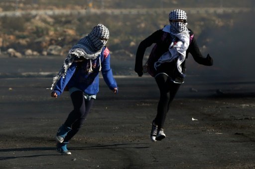 Palestinian female protestors run during clashes with Israeli security forces in the town of al Bireh in the Israeli-occupied West Bank