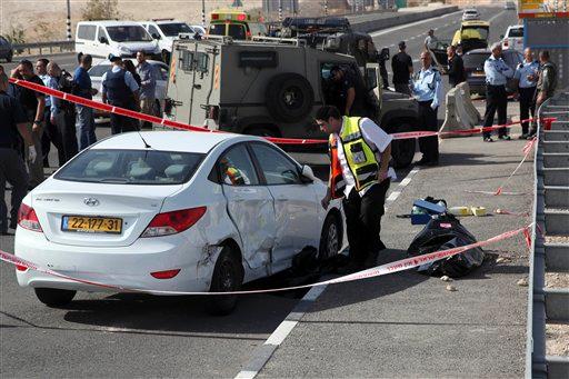 An Israeli emergency service member stands next to the body of an alleged Palestinian attacker near Kfar Adumim settlement in the West Bank Sunday Nov. 22 2015. According to the police a Palestinian driving a taxi cab tried to run over Israelis east