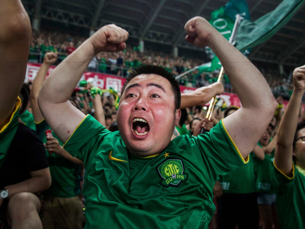 Ultra supporters and fans of the Beijing Guoan FC celebrate together after a goal against Chongcing Lifan FC during their Chinese Super League match