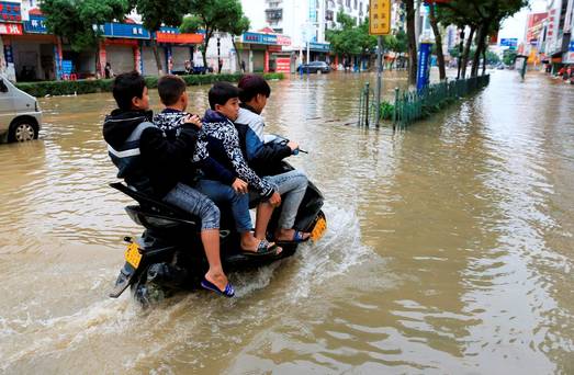 Residents ride a motorcycle along a flooded street after heavy rainfall in Hezhou Guangxi Zhuang Autonomous Region