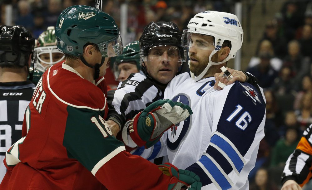 Linesman Mark Wheler separates Minnesota’s Ryan Carter left and Winnipeg’s Andrew Ladd in Friday’s game