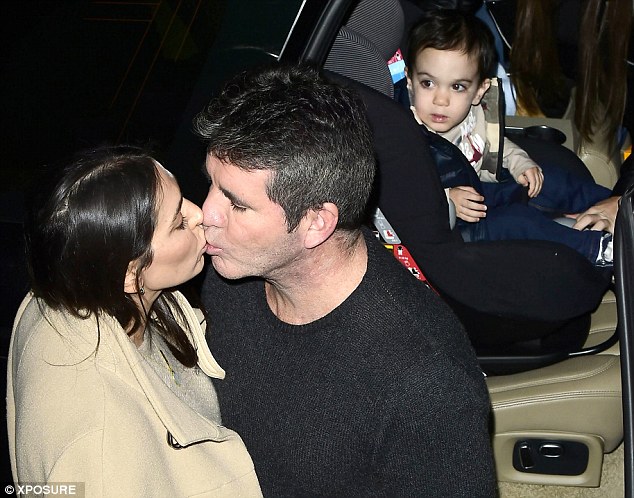 Mwah! Lauren Silverman and Simon Cowell kiss as their young son Eric looks on from his carseat