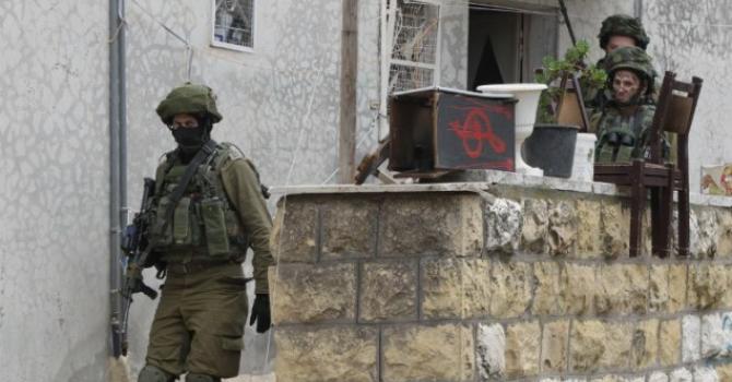 Israeli soldiers search a Palestinian home in the West bank town of Hebron