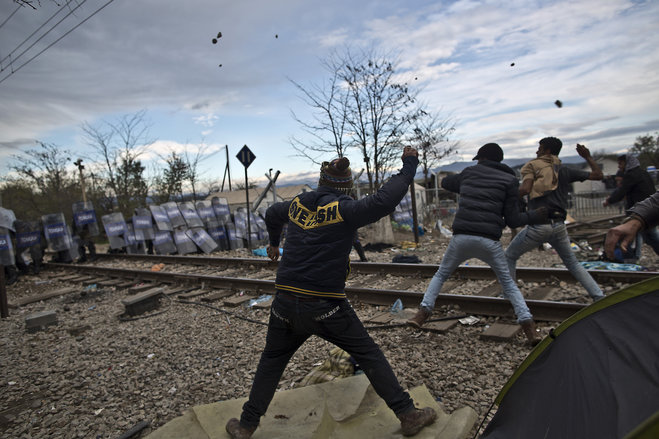 Migrants hurl stones at Macedonian policemen during clashes at the Greek Macedonian border near the northern Greek village of Idomeni on Saturday Nov. 28 2015. Tension has flared on the Greek side of the Greece Macedonia border when a migrant who was