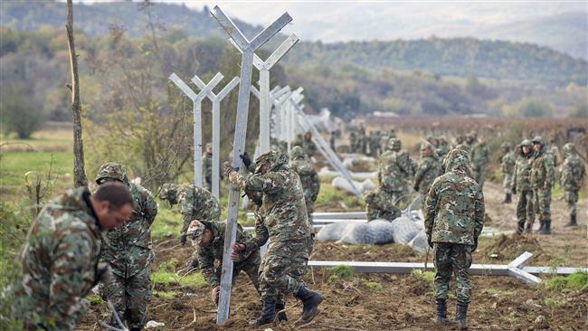 Macedonian soldiers erect poles for a fence to stop refugees crossing the Greek Macedonian border near Gevgelija