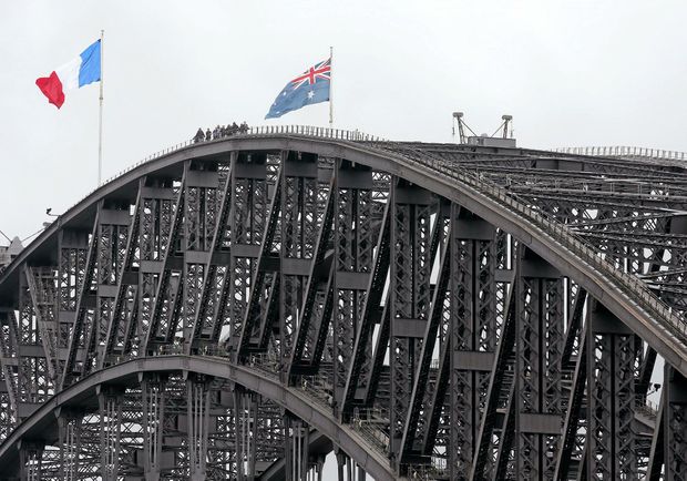 People walk along the top of the Sydney Harbour Bridge where a French flag left is flying alongside an Australian flag in Sydney Sunday Nov. 15 2015. Australian Prime Minister Malcolm Turnbull extended Australia's deep sympathy to the people of F