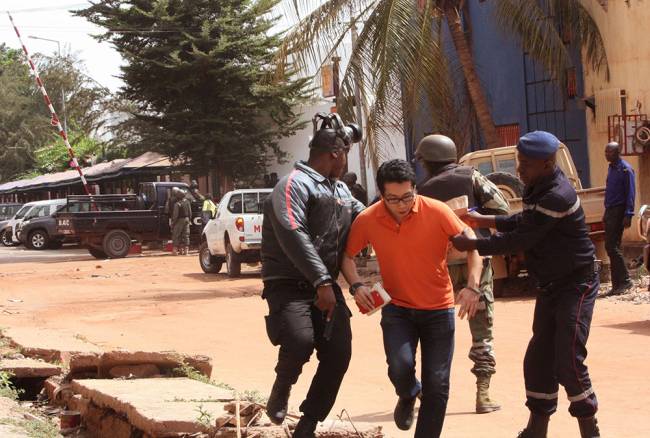 Mali trooper assist a hostage center to leave the scene from the Radisson Blu hotel to safety after gunmen attacked the hotel in Bamako Mali Friday Nov. 20 2015