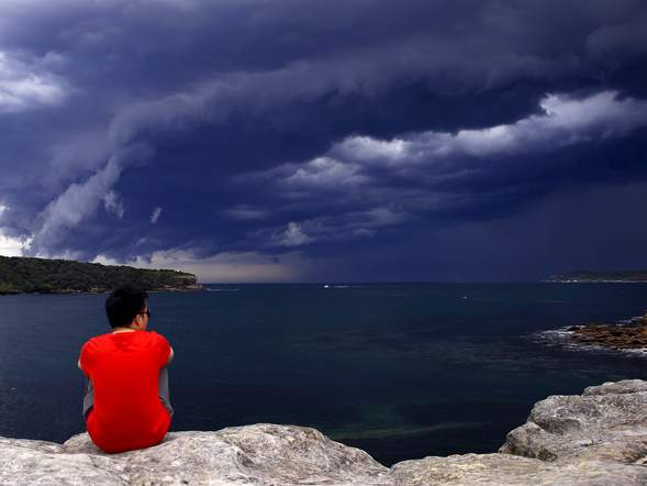 A Chinese tourist watches storm clouds moving along the coast towards the city of Sydney Australia