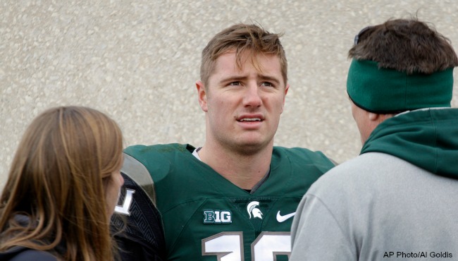 Michigan State quarterback Connor Cook center talks with team trainer Sally Nogle left and his father Chris Cook right following an NCAA college football game against Maryland Saturday Nov. 14 2015 in East Lansing Mich