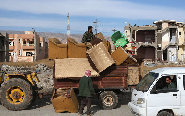 A Yazidi Peshmerga soldier loads household goods onto a trailer in Sinjar Iraq. Local Yazidi fighters who fought with Kurdish forces have been taking any salvageable items out of the rubble