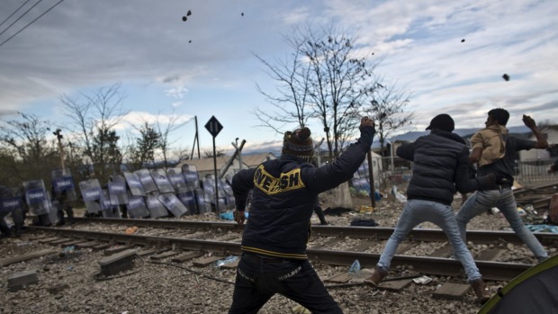 Migrants hurl stones at Macedonian policemen during clashes at the Greek Macedonian border