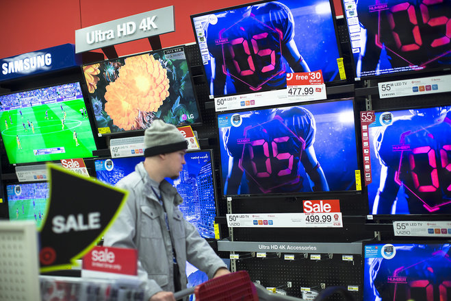 A holiday shopper browses the electronics section against a backdrop of televisions at a Target store Friday Nov. 27 2015 in Newport Ky