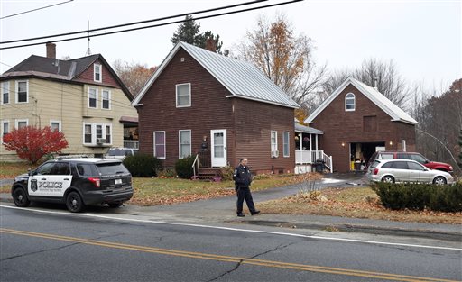 A police officer walks outside a house Thursday Nov. 5 2015 where two women and a man were shot to death in Oakland Maine. Police say the gunman shot himself outside the residence and was found in the driveway