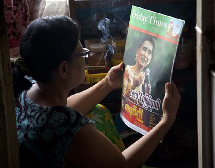 A woman reads a newspaper with Myanmar opposition leader Aung San Suu Kyi on the cover at her residence Thursday Nov 12 2015 on outskirts of Yangon Myanmar. Nobel laureate Aung San Suu Kyi's opposition party was on the verge of a formal victory Thurs