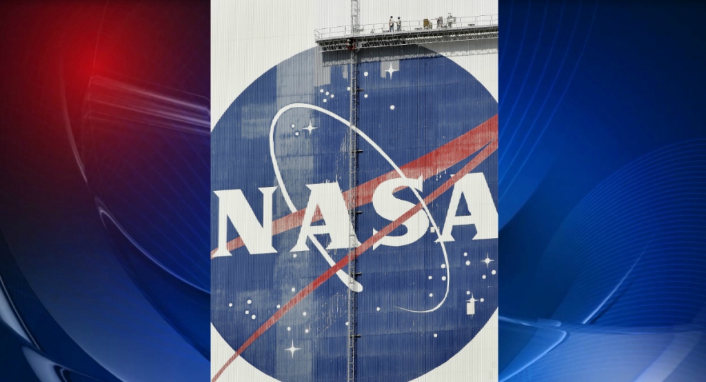 NASA contractors ride a scaffold past the NASA logo on the side of the Vehicle Assemble building Wednesday morning Dec. 6 2006 at the Kennedy Space Center in Cape Canaveral Fla. Workers are continuing to repair tiles from hurricanes that hit the area