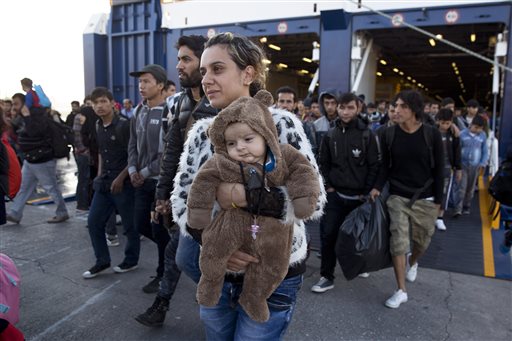 A Syrian woman carrying a baby disembarks from a ferry upon arrival from the Greek island of Lesbos at the Athens&#039 port of Piraeus Wednesday Oct. 14 2015. The International Organization for Migration said more than 593,000 people have crossed this