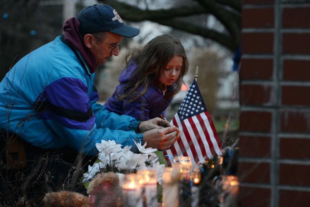 20151129JRNewFlorence6-5 New Florence volunteer firefighter and rescue caption Bernard Sapp helps his daughter Brooke 5 place a candle at a memorial for St. Clair police officer Lloyd Reed on Sunday night