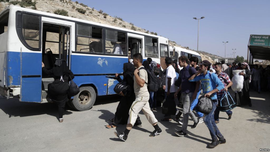 Syrians rush to get on a bus to cross back into Syria at the Syrian Turkish border crossing in Bab al Hawa in Idlib province Syria