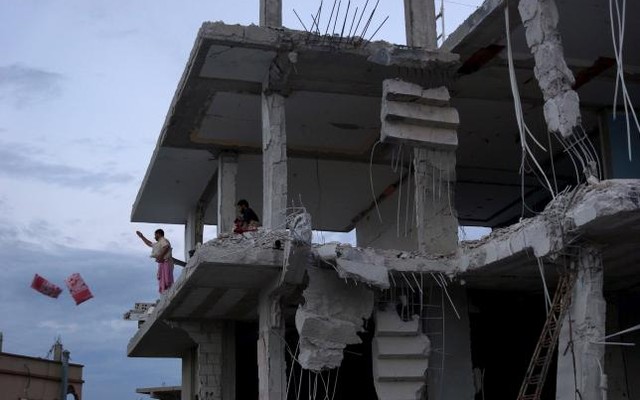 Residents toss belongings from a damaged building from what activists said were airstrikes carried out by the Russian air force in Nawa city Deraa Syria