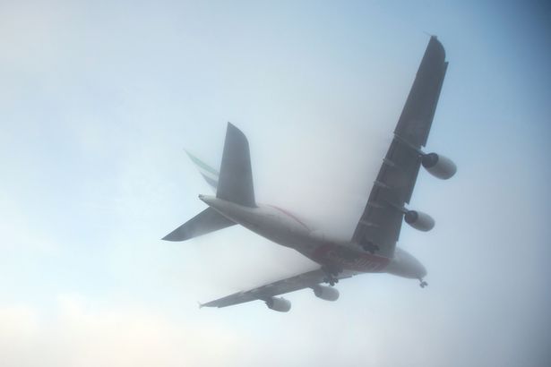 A plane landing in a thick mist as dozens of flights have been cancelled at Heathrow airport due to thick fog