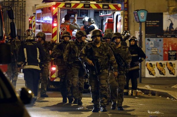 Paris Soldiers walk in front of an ambulance as rescue workers evacuate victims near rue de Charonne