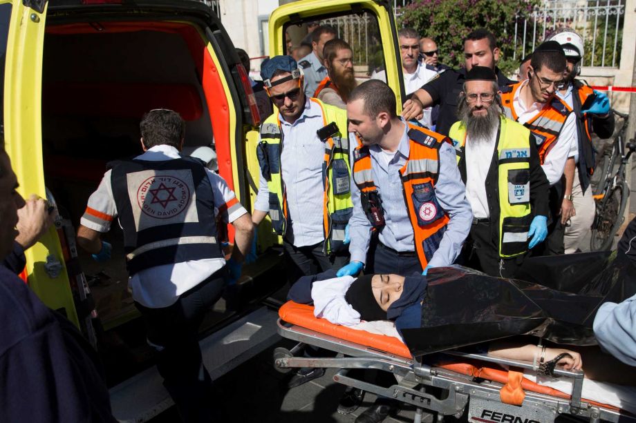 Israeli medics move a handcuffed Palestinian woman who police believe attacked a man at the scene of a stabbing attack in Jerusalem Monday Nov. 23 2015. Two Palestinian teenage girls stabbed a 70-year-old Palestinian man apparently mistaken for an I