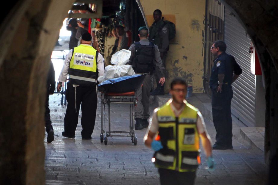 An emergency service member stands next to the body of a Palestinian in Jerusalem's Old City Sunday Nov. 29 2015. A Palestinian stabbed an Israeli police officer in Jerusalem on Sunday before being shot dead by security forces police said