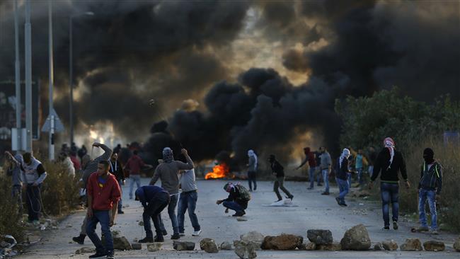 Palestinian protesters throw stones toward Israeli forces during clashes at the entrance of the Palestinian city of al Bireh which lies on the outskirts of Ramallah in the Israeli-occupied West Bank