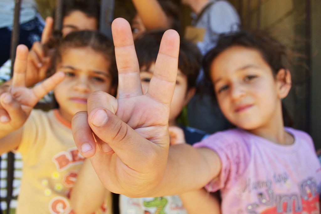 Syrian refugee children at a half-built apartment block near Reyfoun in Lebanon close to the border with Syria give the peace sign. The families fled Syria due to the war and are now living on a building site.- ' BY