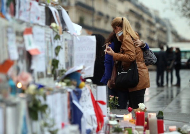 People look at floral tributes and candles left at Place de la Republique in Paris following the terrorist attacks on Friday evening. PIC PA