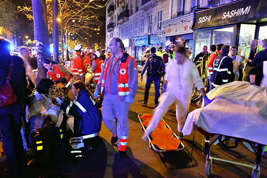 People rest on a bench after being evacuated from the Bataclan theater after a shooting in Paris Saturday Nov. 14 2015