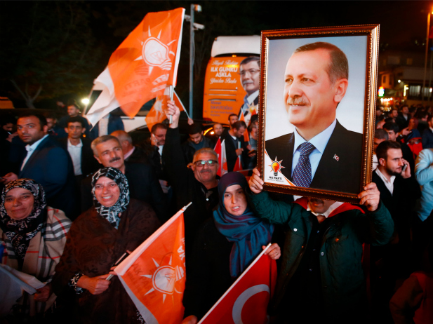 People wave flags and hold a portrait of Turkish President Tayyip Erdogan outside the AK Party headquarters in Istanbul Turkey