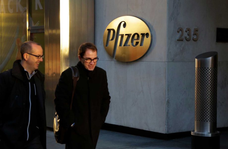 Men pass Pfizer's world headquarters Monday Nov. 23 2015 in New York. Pfizer and Allergan will join in a $160 billion deal to create the world's largest drugmaker